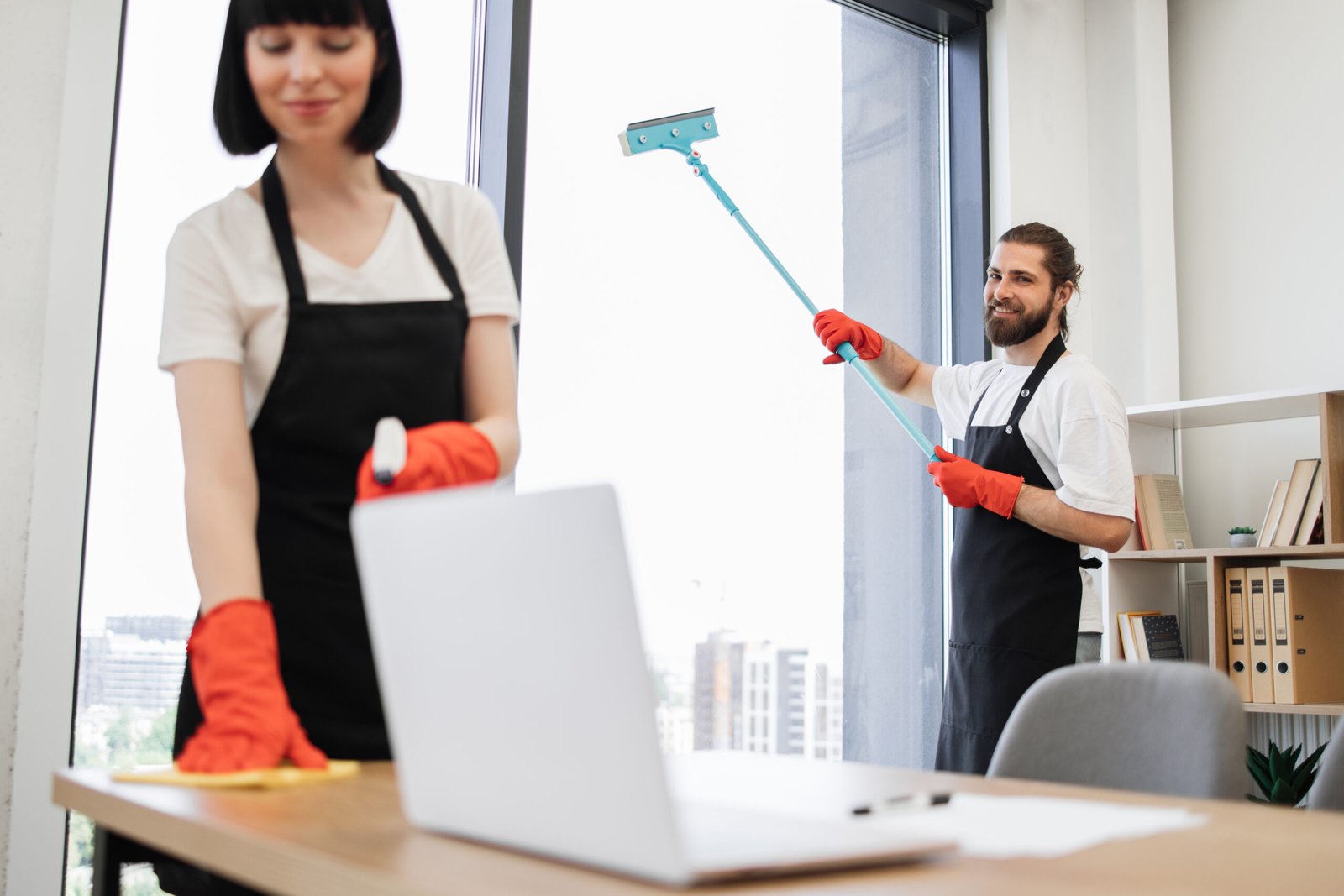 Caucasian worker in a black apron cleaning panoramic window.