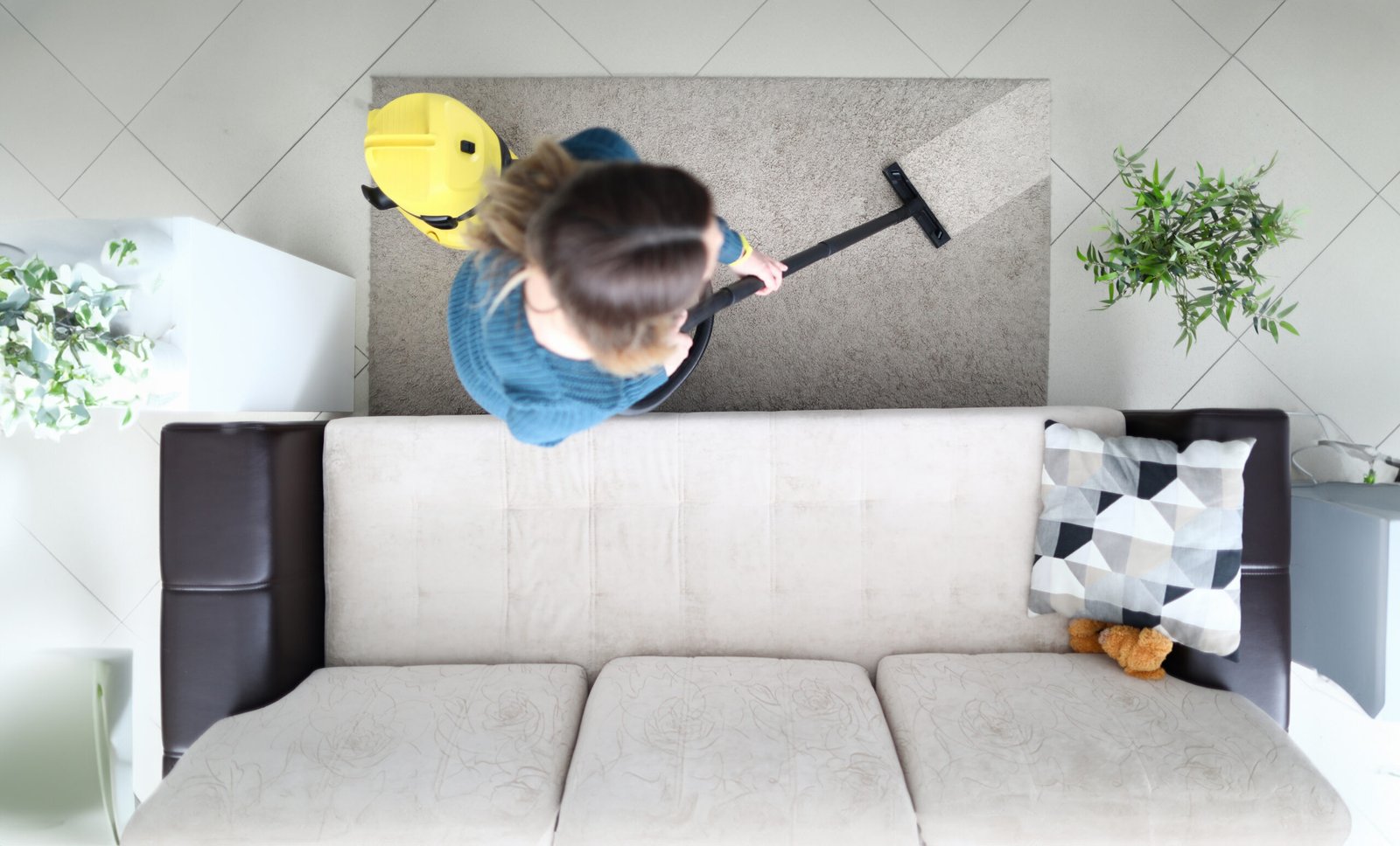 Woman cleaning carpet with vacuum cleaner at home