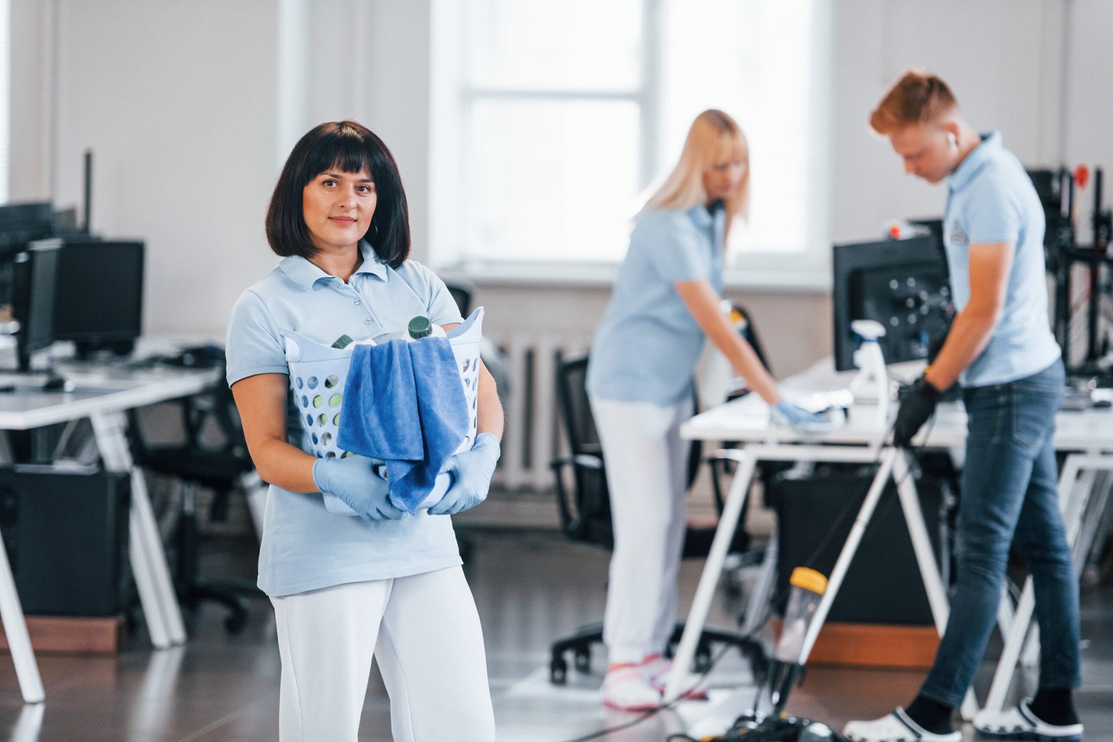 Woman with basket. Group of workers clean modern office together at daytime