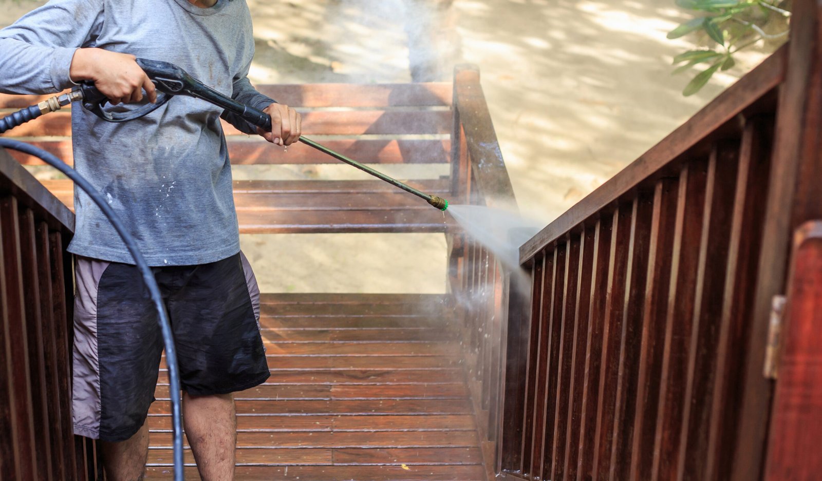 Thai man do a pressure washing on timber